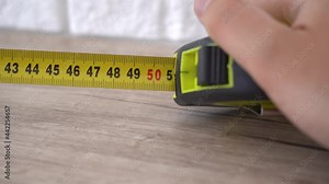 Measuring with yellow tape measure. Hands pull the measuring tape out of tape measure and measure the length. 4k stock footage.