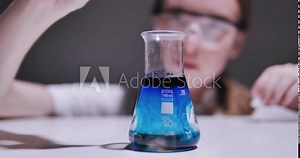 Laboratory worker scientist laboratory assistant tests chemicals for reactions in flask, interfering with different substances and obtaining a visual reaction. Concept of: Science, Chemistry.
