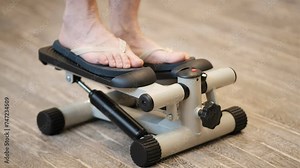 A persons feet are seen actively engaging in a step machine exercise, working to climb up and down the mechanical stairs for a workout session