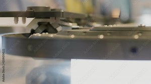 Moving high speed conveyor belt with items on automatic test set, manufacturing process. Details railing on transporter in manufacture. Side view. Industrial transporting process of productions parts