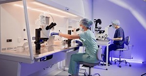 Laboratory worker examining samples under microscope in clinic. An embryologist is seen performing artificial fertilization of a human egg using a microscope in a laboratory setting