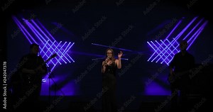 Singer woman on stage, led screen background. The rock vocalist sings a song, concert