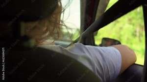 Rear view of a female passenger in a passenger car while traveling on a country highway. Enjoy a summer car ride.