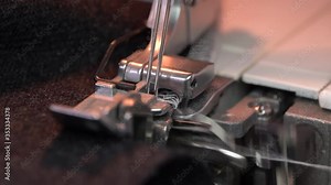 Overlock Sewing Machine. Close up stitches in slow motion. Machine serging the edges of fabric. Presser feet