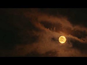 Luna llena amarilla brillando a través de las nubes - 4K