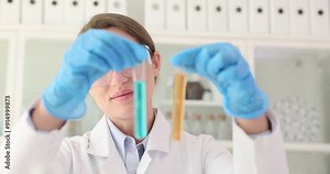 Female scientist scrutinizes multiple test tubes with colorful liquids. Researcher seeks to uncover notable distinctions and commonalities