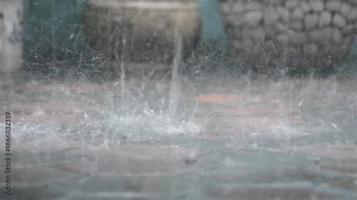 Heavy raindrops falling and splashing on a wet ground surface during a storm