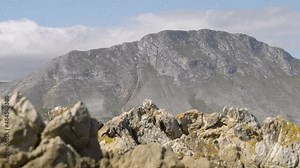 Fast-moving clouds blow over the beautiful biosphere of Kogelberg Mountain Range as seen from a rocky outcrop from Pringle Bay. Daytime.