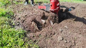 Slow motion view of rotary tiller (also known as rotavator). Cultivation of soil in small farm field. Detail view of agriculture machine.