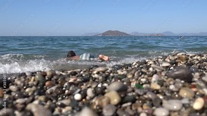 Calis beach, Fethiye, Turkey - 12th of September 2020: 4K Viewing a child in goggles researching underwater life at the beach