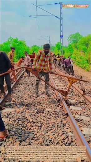A team of workers manually positioning steel rails on a ballast bed