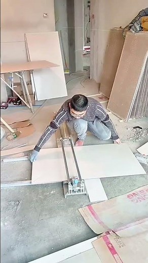 Construction Worker Precisely Cutting a Large Format Ceramic Tile Using a Manual Push Tile Cutter