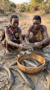 Hadzabe tribe bushman and his wife picking plenty on the mud to cook jollof rice