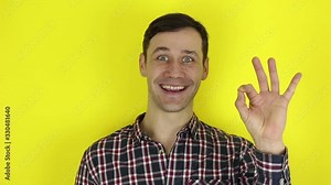 A funny, handsome guy says ok and shows a gesture approval with two hands. Portrait, of a young guy, smiles, and shows gesture ok.