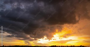 Time lapse of sunset a day to night sequence with clouds moving fast and sun rays glowing onto the high clouds.