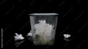 Close-up of throwing crumpled white paper in the metal trash on black background. Tossing paper scrap away gray bin.