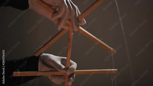 Hands of the puppeteer in white gloves. Marionette control bar with strings