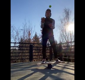 Guy juggling ball while on balance board