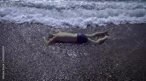 The body of a man washed up on the beach. A drowned man in swimming trunks who was neglected by safety rules on the water.