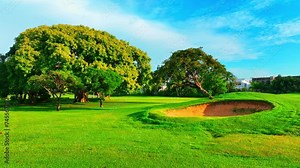 Tropical nature landscape with sand bunker on a beautiful golf course. Green field, trees and blue sky. Golf holidays in the Dominican Republic. Golf course with fairway. Life style.