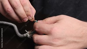A man splices electrical wires. Connects the power cord to the iron. Iron repair at home. Tools for repair are on the table nearby. Close-up.