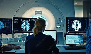 Team of Professional Scientists Work in the Brain Research Laboratory. Neurologists / Neuroscientists Surrounded by Monitors Showing CT, MRI Scans Having Discussions and Working on Personal Computers
