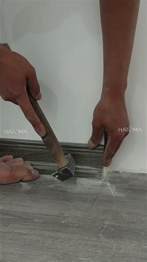 Installing baseboard trim to conceal the joint between the wood-look vinyl flooring and the wall ...