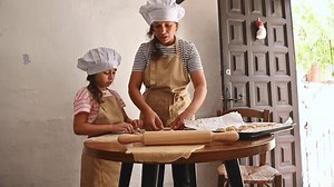 Mutter und Tochter verbinden beim Backen zu Hause, tragen Chefmützen und Schürzen