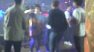 People dance in a nightclub under the light of blue spotlights. Blurry video.