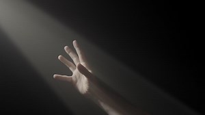 A symbol of hope, a hand reaches for the light amidst darkness