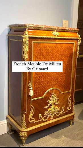 Enveloped in sumptuous parquetry and doré bronze, this majestic Louis XIV-style French meuble de milieu displays the characteristics of incredible quality and masterful workmanship synonymous with the Parisian firm of Maison Grimard. Crafted of sumptuous kingwood, the parquetry door opens to reveal six compartments used to store linens, such as those for the bedroom or even the dining table. The masterful woodwork is flawlessly balanced by intricate doré bronze mounts in the form of Neoclassical