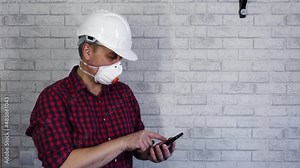 A male builder calculates the costs on a calculator. Construction estimate. The cost of a new house. A builder in a white helmet on a construction site