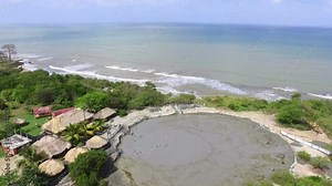 People bathing in the Arbolete mud volcano drone aerial. Hot mud pool in the crater of a volcano in Antioquia, Colombia. Many neighbors visit their therapeutic baths by the sea.