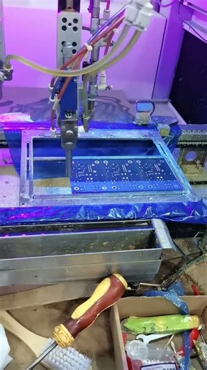 The machine is spraying a protective lacquer on the PCB.