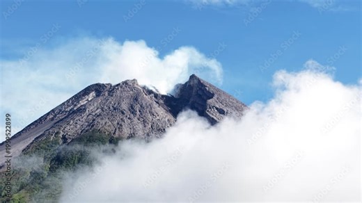 4K aerial footage shows the peak of Mount Merapi in Yogyakarta covered in thick clouds, with clear blue skies.
