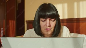 In this inspiring video, a young woman shows that working from home during quarantine can be enjoyable as she smiles, types on her computer, and sends emails while comfortably sitting on her sofa.