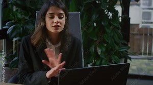Young woman is making a video call in the office. Zoom or webinar, a female manager talks to clients. A businesswoman conducts a training session or a virtual meeting on a laptop. Customer support