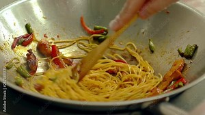 CU, Slow motion: Cook prepares noodles (pasta) in a frying pan, in oil, with fresh vegetables - potatoes, tomatoes, green beans, bell peppers and shrimps, stir.