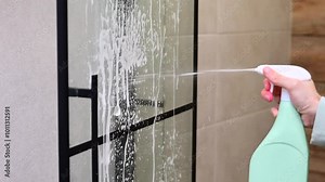 cleaning the bathroom, woman washing the glass wall in the shower