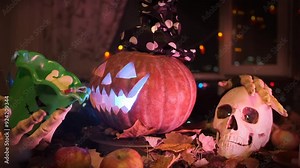 Male hand puts candy into a Halloween pumpkin bucket with skeletal hands stroking a human skull in the thick night fog, party background.