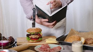 Female Chef cooking Big Burger or Cheeseburger and looking to a Textbook with Cooking Recipe Tutorial.