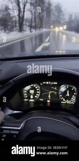 Driving through challenging wet weather conditions, the windshield wipers clear rain and snow. The dashboard displays the cars speed and navigation system, highlighting a demanding journey Stock Video Footage - Alamy