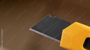 Yellow utility knife on a open parcel box background. Retractable cardboard cutter close up