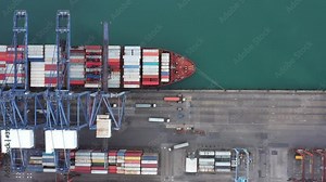 Aerial top view over international cargo ship at industrial import-export port prepare to load containers with big container loader ship vessel. Oversea international Business.