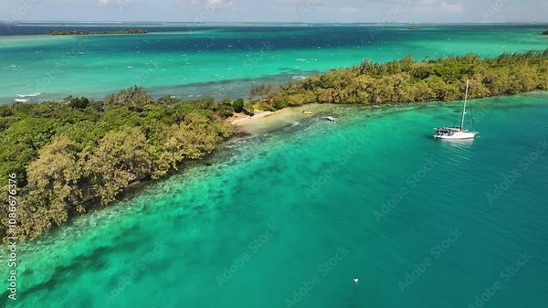 Small sandy beach in remote Pacific Island, coral reef and sailing boat. Beautiful sunny day in Tonga.