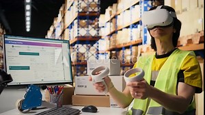 Worker uses virtual reality headset to ensure order fulfillment with AI, tracking parcel status for e-commerce logistics. Asian man in industrial depot with racks and boxes. Camera A.