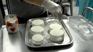 Woman making cheese from sheeps milk. Cheese maker sprinkles salt on freshly fermented cheese. Food industry: Making cheese at dairy factory.