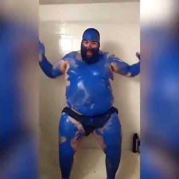 fat guy in blue paint loudly screams in a bathtub while vigorously slapping himself
