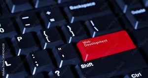 Human finger pushing a red button with text of Web Development on the computer keyboard