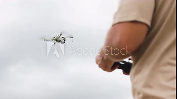 Drone development engineer tests new model in field. Tester deftly operates quadcopters remote control. Drone obeys engineers commands. Process of testing new drone model.